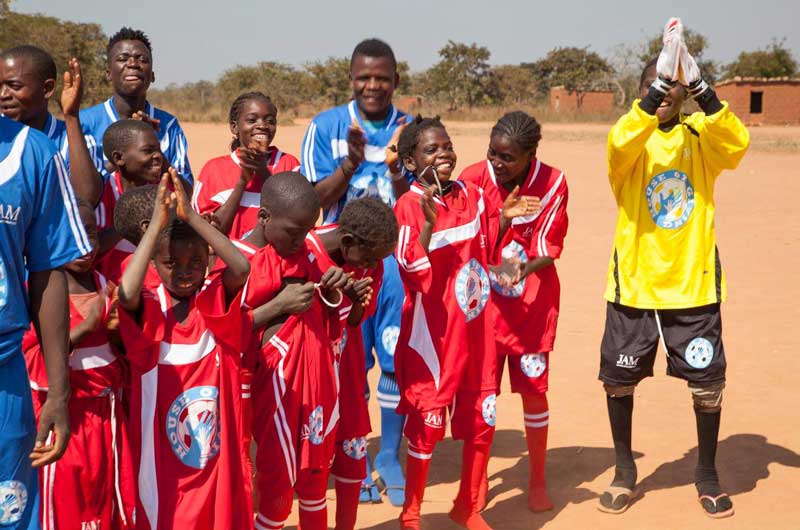 Group of kids on a soccer field. with House of Giving jerseys