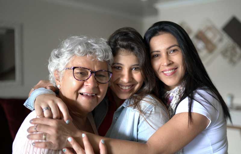 Three Latina Women hugging and smiling at the camera