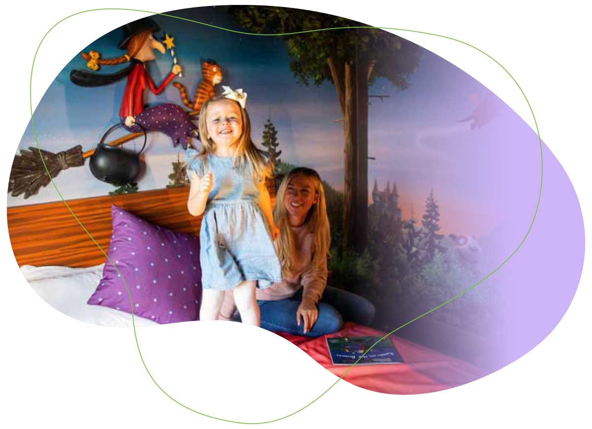 Little girl jumping on bed with fairy theme painted onher wall