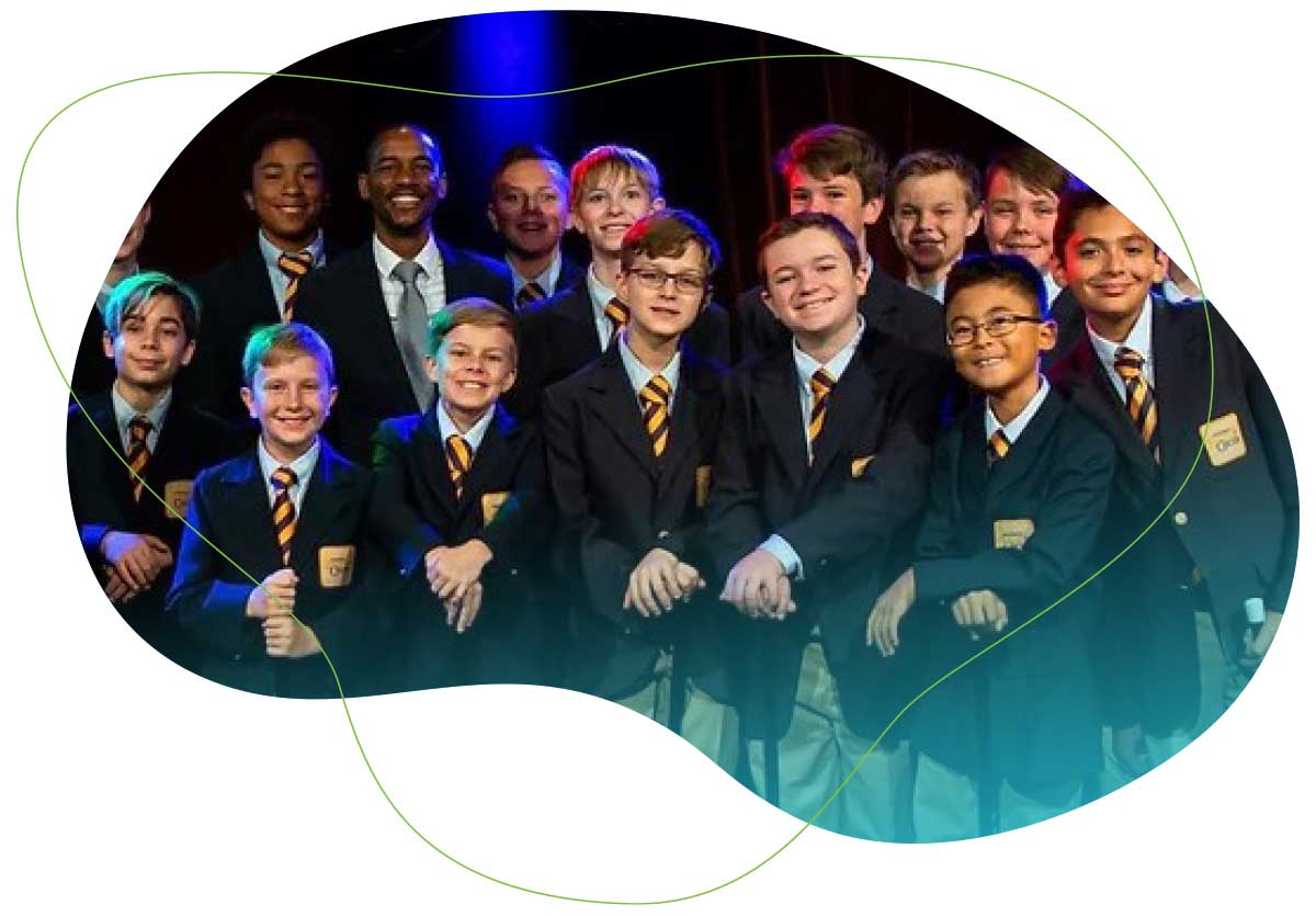 Image of choir boys smiling and dressed in blue blazers and snazzy ties.